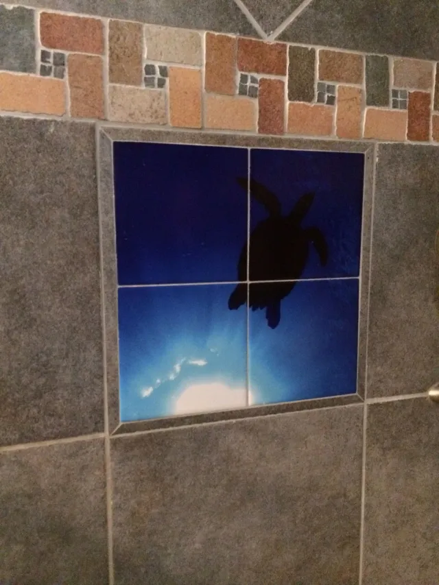 Blue tile mural of a silhouetted skydiver, framed by gray and brick wall tiles.